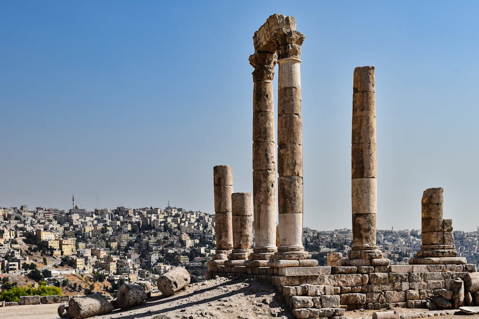 Ancient Roman temple columns in Amman with cityscape in the background under clear skies.